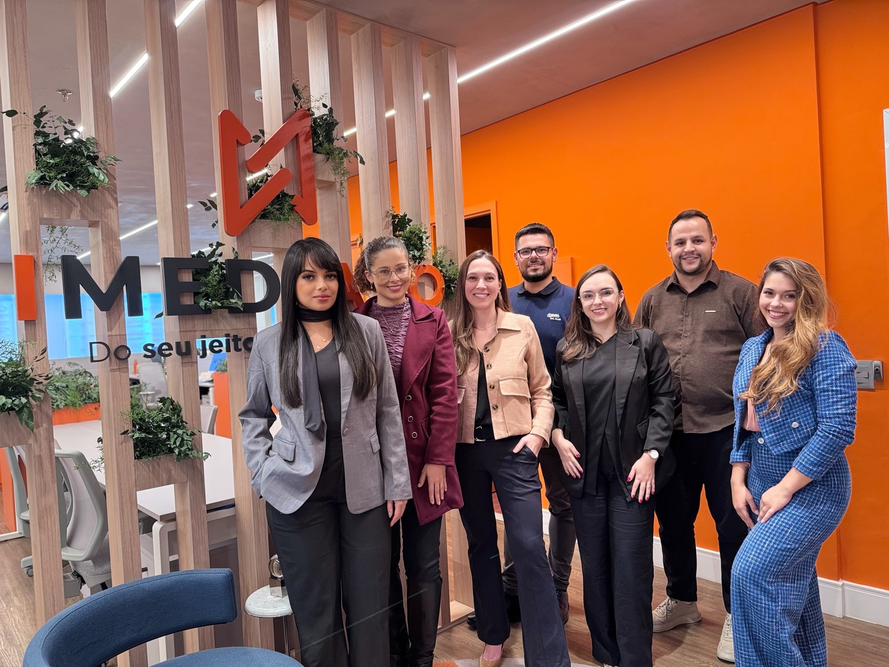 Equipe Imediato em frente ao logo da empresa